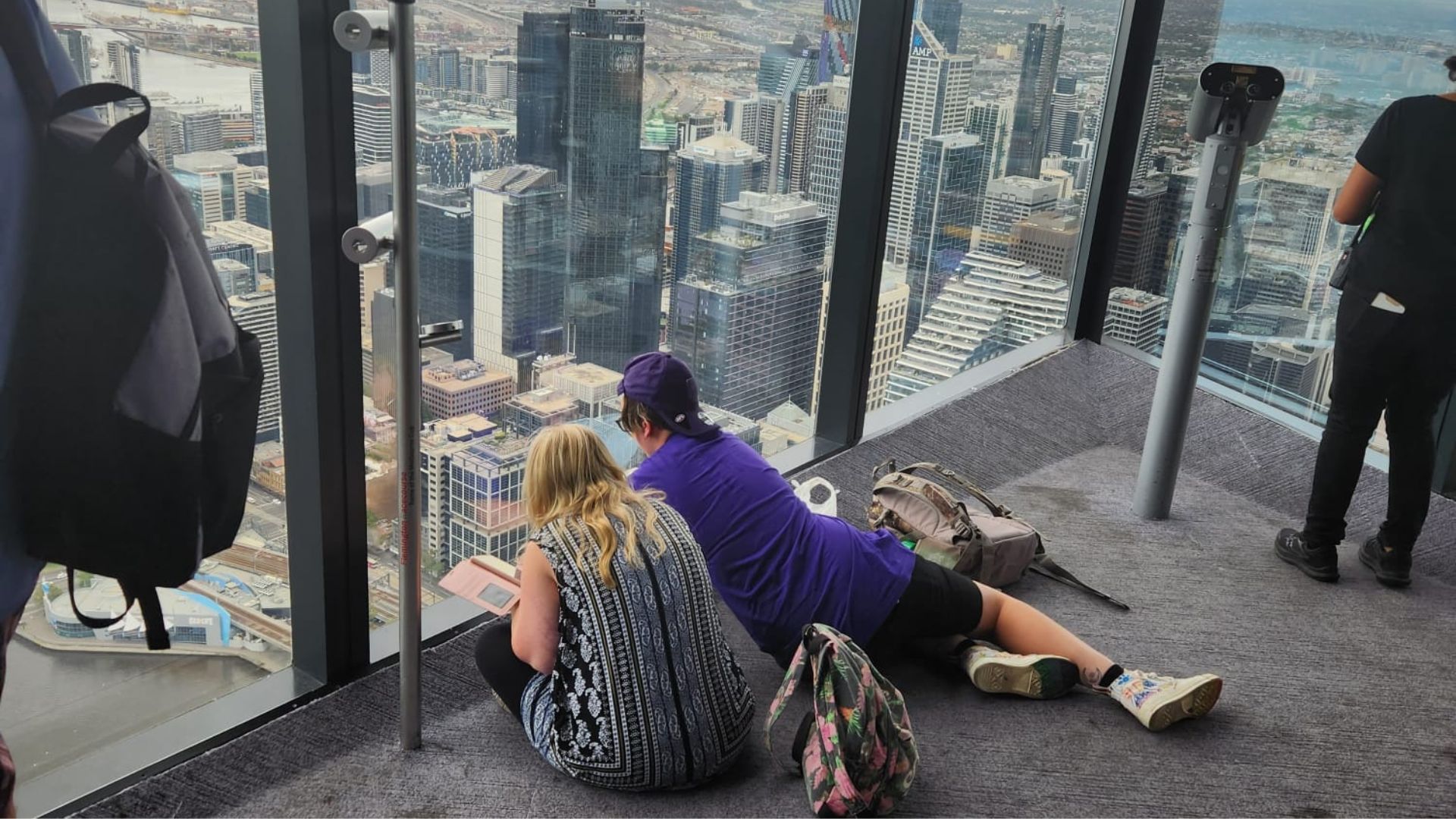 Participant and Volunteer staring out of a high-rise building window onto the city below.